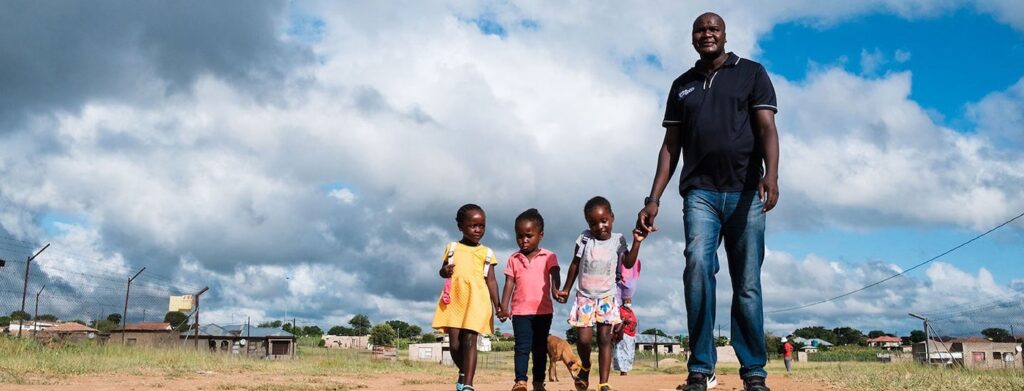 a man taking three children to their preschool