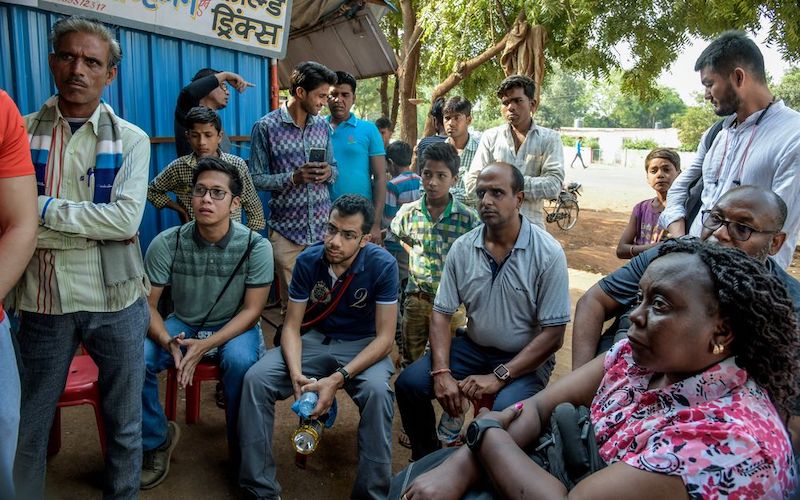 un groupe d'hommes et une femme indienne assis ou debout tout en écoutant quelqu'un