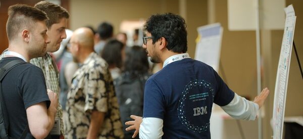 People gathered around a poster board engaged in conversation.